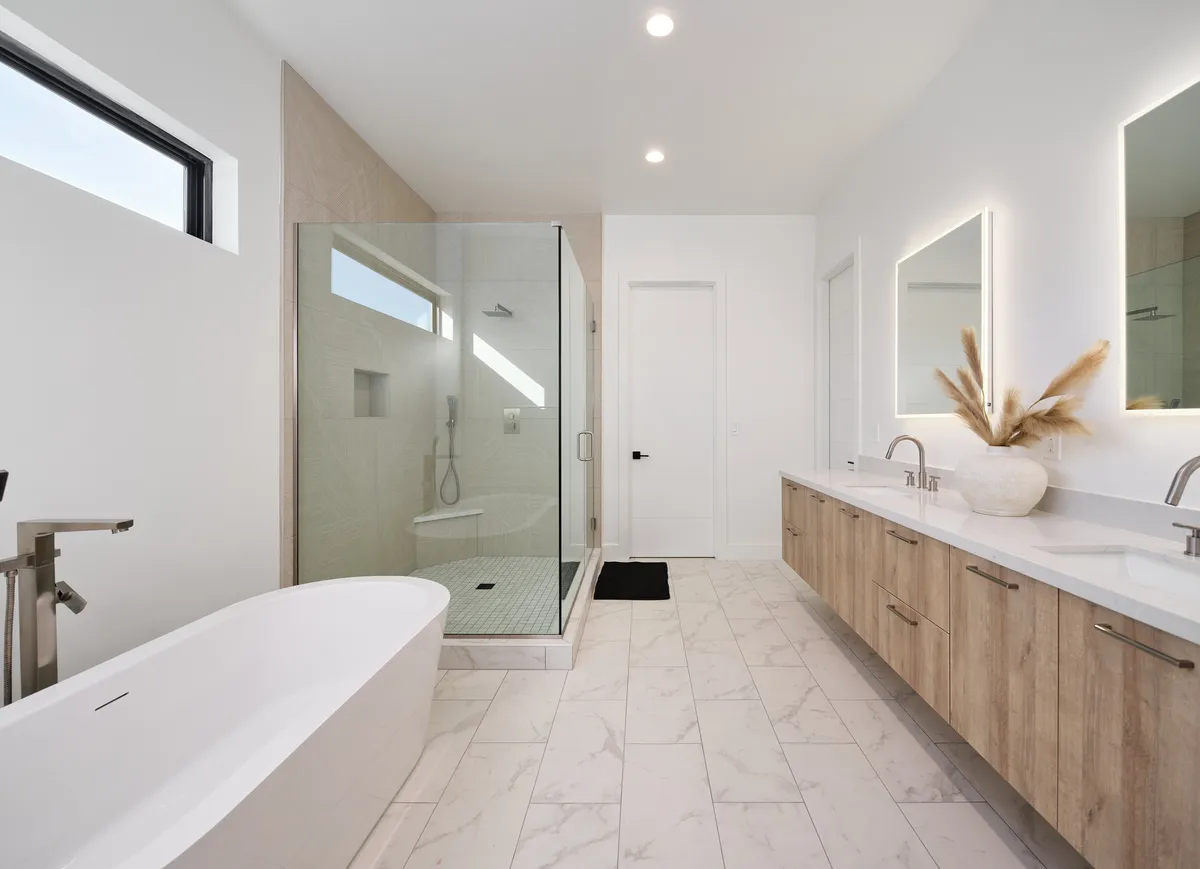 A luxurious ensuite bathroom featuring a freestanding soaking tub, glass shower enclosure, and a double vanity with modern mirrors. The ambiance is serene and spa-like, designed for relaxation and rejuvenation after a day of adventure.