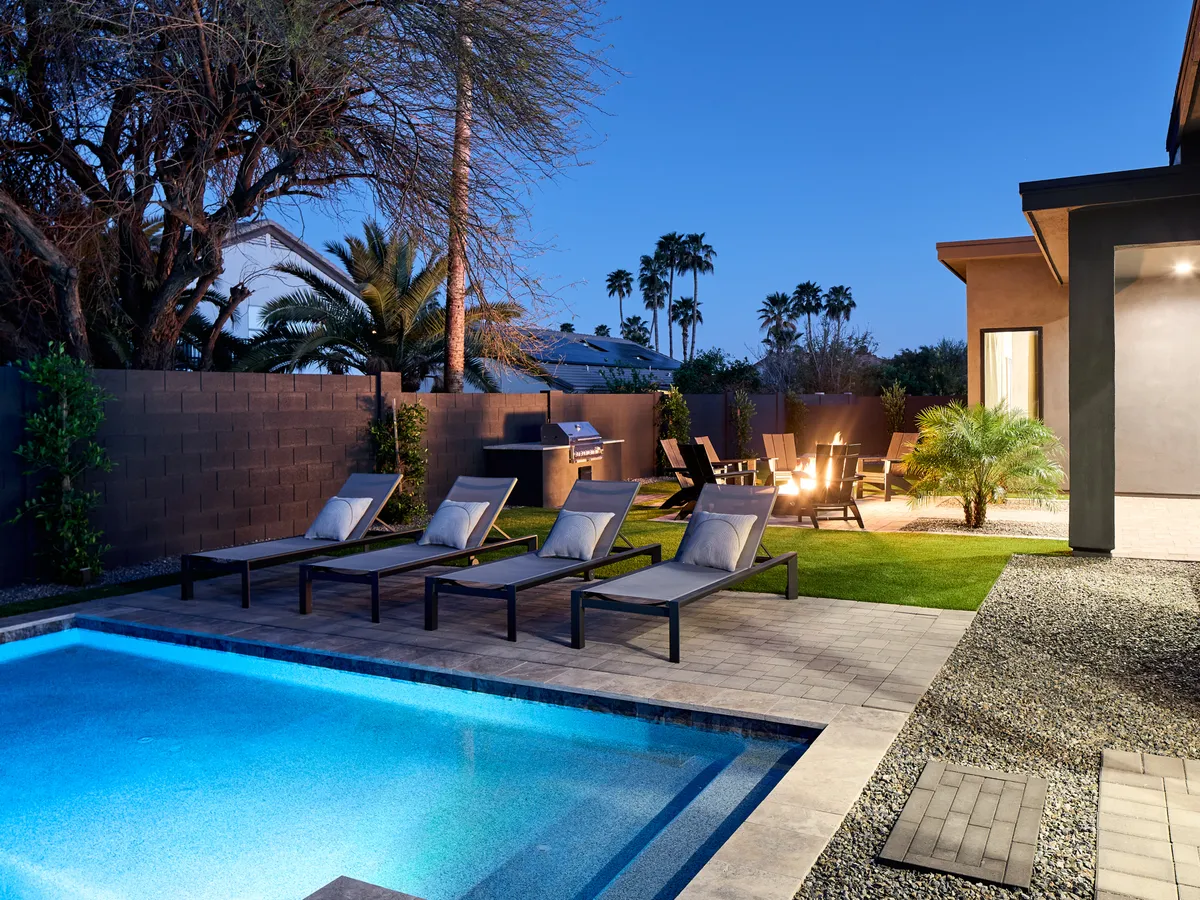 This inviting exterior view captures a sparkling swimming pool surrounded by lounge chairs, a cozy fire pit, and outdoor seating. The mood is relaxed and social—perfect for family gatherings, s’mores nights, and sun-soaked play after a day of adventure.