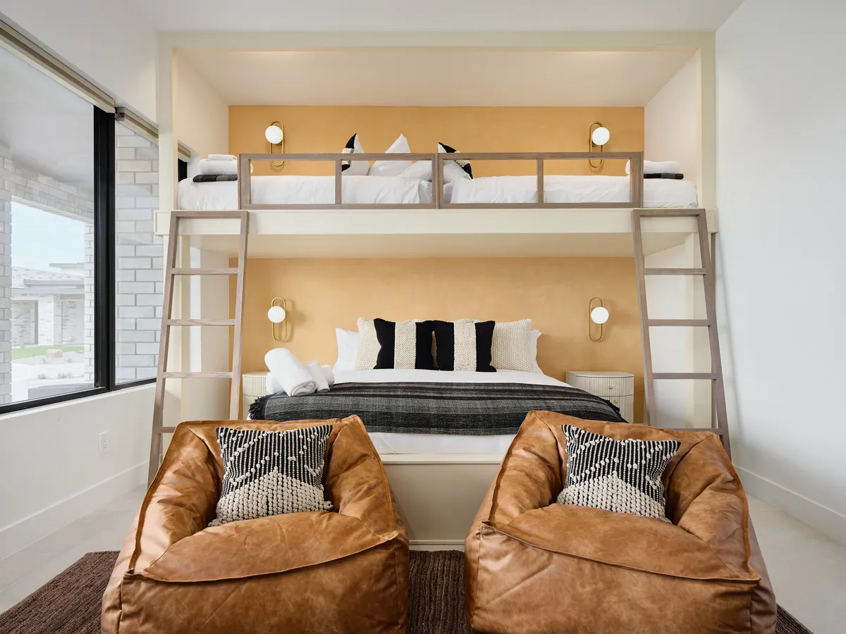 A playful bunk room with custom-built bunk beds—two twins above a king—accompanied by cozy bean bag chairs and a textured accent wall. The space feels relaxed and inviting, perfect for families or groups with children.